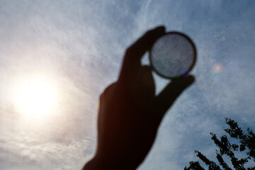 Hand hold Polarizing filter against blue sky. Light background.