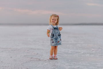 Little girl meets sunset on firth kuyalnik when it's coast is white because of the salt
