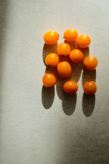 Organic sea buckthorn with deep shadows. Layout on grey background, flat lay. Fresh orange berries in bright sunlight. Natural valuable food supplement.