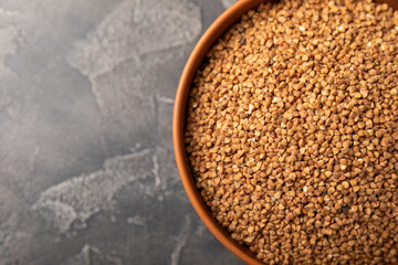 Buckwheat in a bowl on a black marble background. Raw buckwheat. Ingredients for gluten-free porridge.Healthy food. Place to copy.