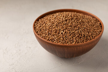 Buckwheat in a bowl on a gray marble background. Raw buckwheat. Ingredients for gluten-free porridge.Healthy food. Place to copy.