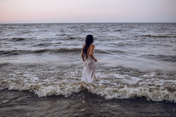 a girl in a white dress enters the stormy sea