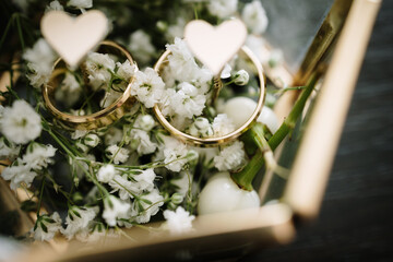 White flowers and two golden wedding rings on flower background - obrazy, fototapety, plakaty