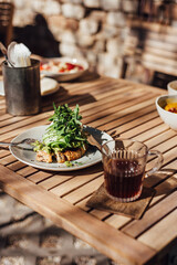 cup of coffee on a wooden table, scrambled eggs on bread with arugula on a plate, breakfast, lunch in a cafe