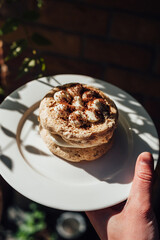 meringue cake on a plate held in the hand in the sunlight, sweets in a restaurant