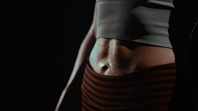 Close-up stomach with press on a girl wet from sweat after workout in gym