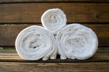 Obraz na płótnie Canvas Three Rolled Towels on a Bench