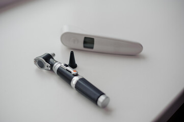 Non-contact thermometer on a white background for measuring body temperature. Otoscope on a white background, a device for examining the auricle and middle ear