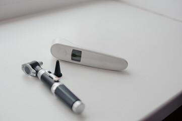 Non-contact thermometer on a white background for measuring body temperature. Otoscope on a white background, a device for examining the auricle and middle ear