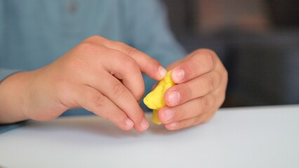 Close-up view of little hands sculpts a figure using fork