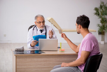 Obraz premium Young male patient visiting old male doctor