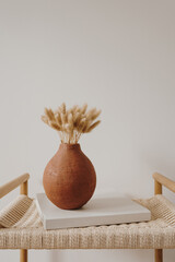 Bunny tail grass bouquet in elegant clay pot on rattan bench. Aesthetic minimal modern Scandinavian interior design decoration - obrazy, fototapety, plakaty
