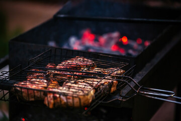 large pieces of juicy meat are fried outdoors on the grill on burning coals