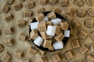 Natural,brown sugar cubes designed in bamboo bowl with white sugar cubes on granulated brown...