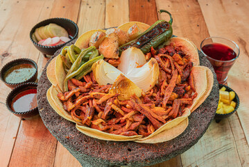 Tradicional orden de tacos mexicanos al pastor servido en un molcajete, en una mesa de madera con...