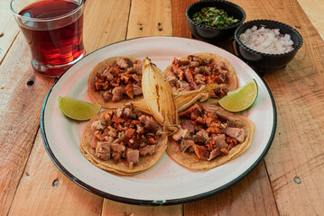 Tradicionales tacos mexicanos combinados servidos en una mesa con salsas y agua fresca de jamaica