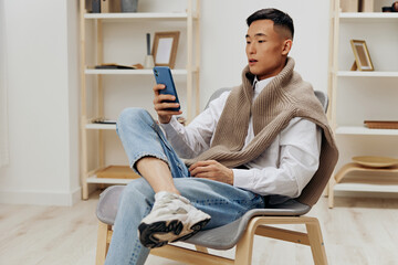 handsome man sitting in a chair in a room with phone on his lap