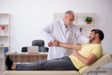 Obraz premium Young male patient visiting old male doctor chiropractor