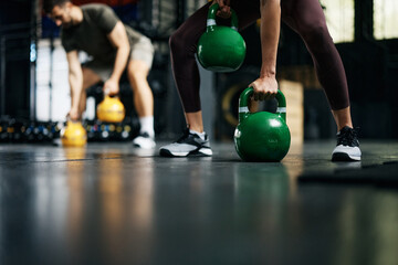 Close up of athletic woman having cross training with kettlebells in gym.