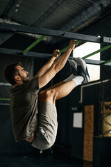 Fototapeta na wymiar Male athlete exercising on hanging ladder during cross training in gym.