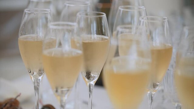 Misted glass goblets with chilled champagne stand on table on hot day. Bubbles rise from bottom of glass to surface.