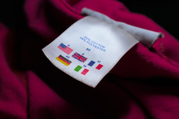 Size tag of a Red cloth describing  different country size comparisons 