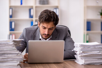 Young male employee unhappy with excessive work in the office