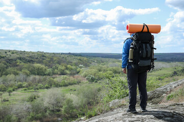Hiker with backpack ready for journey on rocky hill, back view