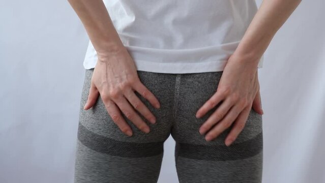 The girl touches and kneads her buttocks. Beautiful in sports tight leggings. Muscle pain after training, krepatura. The girl makes the muscles of the buttocks contract. Sports leggings