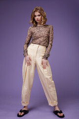 High fashion photo of a beautiful elegant young woman in a pretty beige cream linen trousers,...