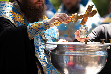 Orthodox priest blesses water with a cross