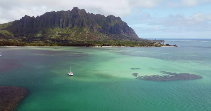 Aerial panorama above calm colorful ocean with scenic reefs and  Koolau Mountains in Kaneohe Bay, Oahu Island, Hawaii