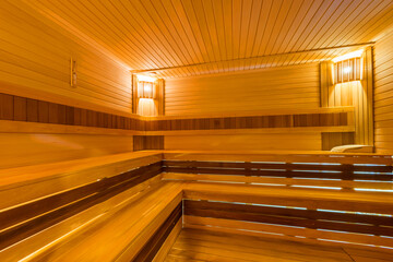 Sauna room with original decoration of benches and walls. Cozy soft lighting.