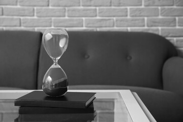 Hourglass and notebooks on table in living room, closeup