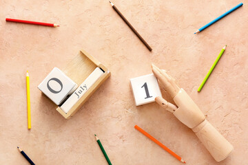 Wooden hand with cube calendar and colorful pencils on beige background