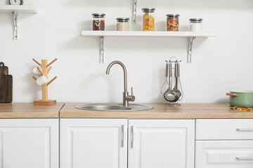 Interior of light kitchen with white counters and utensils