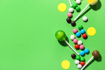 Composition with sweet lollipops and colorful candies on green background