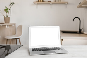 Laptop with blank screen on counter in light kitchen