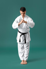 Man performing ritual bow before practicing karate on green background