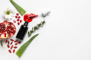Bottle of natural serum with pomegranate, plant leaves and daisy flower on white background