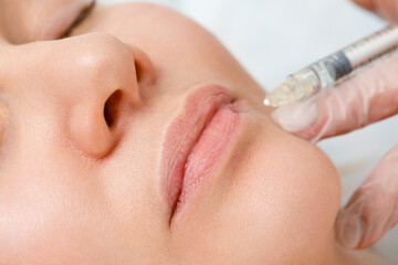 Lip shape correction procedure in a cosmetology salon. The specialist makes an injection on the...