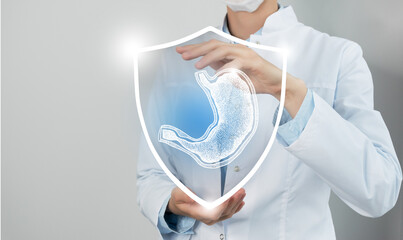 Unrecognizable female doctor holding shield and graphic virtual visualization of Stomach organ in...