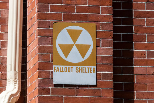 Orange "Fallout Shelter" sign on a brick wall. With global instability, Fallout Shelters may become more popular.