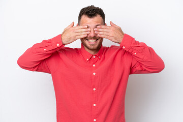 Young Brazilian man isolated on white background covering eyes by hands and smiling