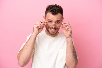 Young brazilian man isolated on pink background With glasses with happy expression