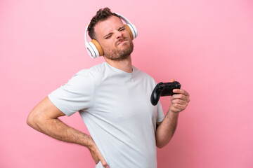 Fototapeta na wymiar Young Brazilian man playing with video game controller isolated on pink background suffering from backache for having made an effort