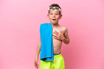 Little caucasian boy wearing a diving goggles isolated on pink background surprised and shocked while looking right © luismolinero