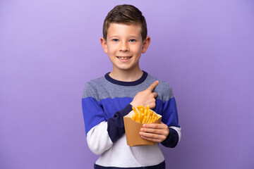 Little boy holding fried chips isolated on purple background pointing to the side to present a product