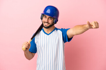 Baseball player with helmet and bat isolated on pink background giving a thumbs up gesture