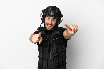 Young caucasian swat isolated on white background points finger at you while smiling